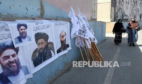  Wanita Afghanistan berjalan di dekat poster pemimpin Taliban dan bendera di Kabul, Afghanistan, Rabu (25/8). Taliban merebut kembali kendali atas Afghanistan hampir 20 tahun setelah mereka digulingkan dalam invasi pimpinan AS setelah serangan 9/11. 