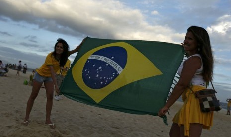 Wanita Brasil membentangkan bendera negaranya sebelum Timnas Brasil menghadapi Kroasia di laga Grup A Piala Dunia 2014 di pantai Copacabana, Rio de Janeiro, Kamis (12/6). 