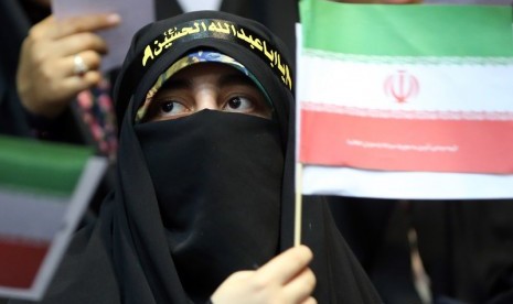 Wanita memegang bendera Iran.