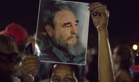 Wanita mengangkat foto mendiang Fidel Castro dalam reli di Revolution Plaza di Havana, Kuba, (29/11). Sekolah dan kantor pemerintah diliburkan untuk menghormati jenazah Castro.