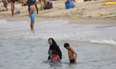 Muslim Prancis Merasa Tertekan Terima Piagam Nilai Republik. Wanita mengenakan baju renang Muslim yang tertutup penuh atau burkini di Pantai Marseilles, Prancis.