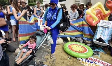 Wanita mengenakan burkini dalam rangka gerakan 'Wear What You Want Beach Party' di luar Kedubes Prancis di London. Aksi protes ini dilakukan untuk menunjukkan solidaritas terhadap Muslim Prancis.