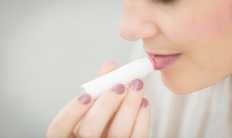 Wanita menggunakan lip balm atau pelembab bibir.