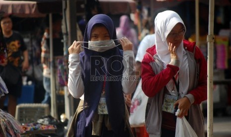 Wanita menggunakan masker untuk menghindari polusi udara.