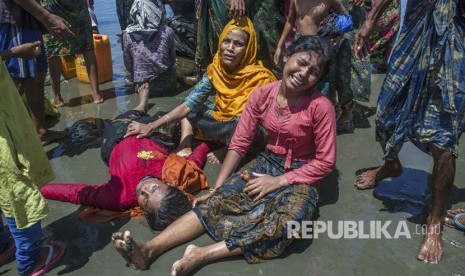 Wanita Muslim Rohingya, yang menyeberang dari Myanmar ke Bangladesh, meratap karena kerabatnya tidak sadar setelah kapal yang mereka tumpangi berbaris beberapa menit sebelum mencapai pantai di Shah Porir Dwip, Bangladesh,Kamis, (14/9).