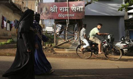 Wanita Muslim tak dikenal berjalan melewati papan yang menampilkan nama kelompok nasionalis Hindu Sri Ram Sena Hindustan di lingkungan perumahan di Belagavi, India, 7 Oktober 2021. Polisi di tempat lain di India telah menangkap seorang pria yang diduga berada di balik penawaran untuk dijual wanita Muslim terkemuka melalui lelang online palsu, dalam kasus yang telah memicu kemarahan dan kemarahan di seluruh negeri. Penelitian Terbaru Ungkap Diskriminasi Ganggu Kesehatan Mental Muslim India