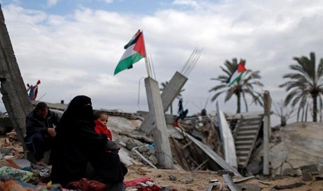 Wanita Palestina berkumpul di dekat rumahnya yang hancur di selatan Jalur Gaza, Senin (13/1). Memasuki musim dingin warga Palestina harus berjuang melawan hawa dingin yang akan mecapai puncaknya pada bulan ini. 