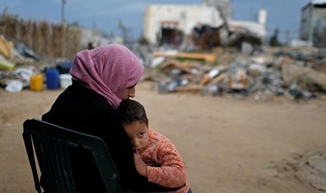 PBB: Pengungsi Palestina Butuh Bantuan Rp 1,4 Triliun. Wanita Palestina bersama anaknya di dekat rumahnya yang hancur di selatan Jalur Gaza.