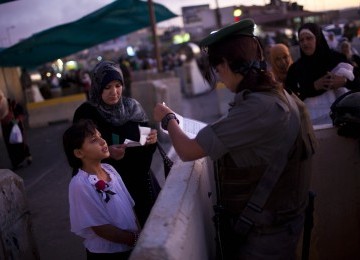 Wanita Palestina dan anaknya menjalani pemeriksaan oleh serdadu Israel di pos penyeberangan Qalandia, Jumat (5/8). Warga Palestina asal Tepi Barat berbondong-bondong menuju Masjid Al Aqsa di Yerussalem (Ilustrasi)