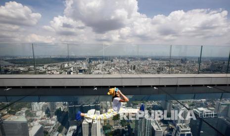  Wanita Thailand memegang kacamata khusus untuk menyaksikan gerhana matahari annular parsial di Mahanakhon Skywalk Glass Tray di Bangkok, Thailand, Ahad (21/6/2020). 