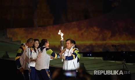 Wapres Jusuf Kalla (kanan) disaksikan legenda bulu tangkis Indonesia Susi Susanti (kedua kiri) dan mantan atlet tenis Yustedjo Tarik (kiri) menyerahkan api obor Asian Games 2018 yang telah disatukan kepada mantan atlet bulu tangkis Finarsih (kedua kanan) saat Asian Games 2018 Torch Relay Concert di Kompleks Candi Prambanan, Sleman, DI Yogyakarta, Rabu (18/7). 