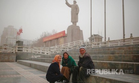 Warg aetnis Uighur dengan latar patung mendiang pemimpin China Mao Zedong di  Khasgar, Daerah Otonomi Xinjiang Uighur, China.