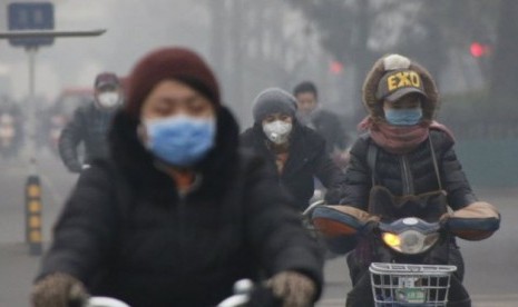 Warga Beijing beraktivitas di tengah asap dan kabut.