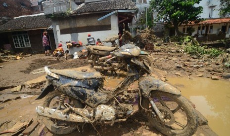 Warga berada di dekat barang-barang yang terselamatkan dari puing bangunan rumah yang roboh akibat diterjang banjir bandang aliran Sungai Ciamanuk di Kampung Cimacan, Kecamatan Tarogong, Kabupaten Garut, Jawa Barat, Rabu (21/9).