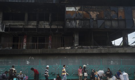 Warga berada di dekat deretan kios yang terbakar di Pasar Senen, Jakarta Pusat, Jumat (20/1). 