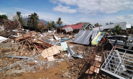 Warga berada di dekat rumah dan bangunan yang luluh lantak akibat gempa di Desa Lolu, Sigi, Sulawesi Tengah, Senin (8/10).