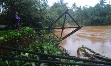 Warga berada di dekat sisa tiang jembatan gantung yang ambruk terbawa arus sungai Cibeurem, Desa Pajaten, Kabupaten Pangandaran, Jawa Barat, Sabtu (7/10). Hujan deras yang mengguyur wilayah Pangandaran mengakibatkan air sungai Cibeurem meluap serta mengikis jembatan.