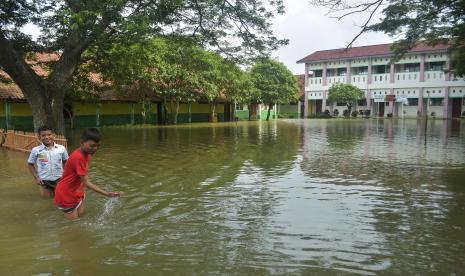 Warga berada di depan rumah yang terdampak banjir di Desa Buni Bakti, Babelan, Kabupaten Bekasi, Jawa Barat, Kamis (20/1/2022). Banjir setinggi 30-60 cm dari luapan sungai irigasi, sejak tiga hari lalu menggenangi rumah warga.