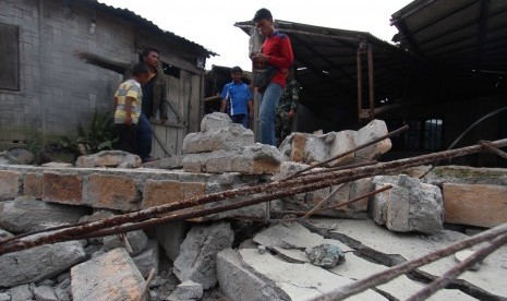 Warga berada di rumah yang runtuh akibat gempa di Desa Kabayaken Kecamatan Namanteran, Kabupaten Karo, Sumatera Utara, Senin (17/1).