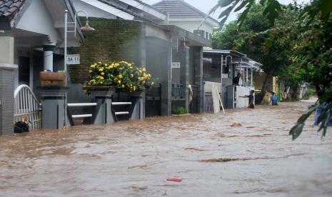 Warga berada di rumahnya ketika terjadi banjir di Perumahan Bumi Mangli, Kaliwates, Jember, Jawa Timur, Ahad (9/1/2022). Hujan dengan intensitas sedang hingga lebat yang terjadi disebagian wilayah di Jember, menyebabkan saluran air tidak mampu menampung debit air yang mengakibatkan sekitar 100 rumah warga terendam.