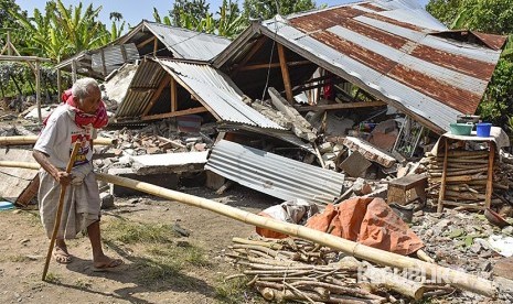 Warga berada di rumahnya yang rubuh akibat gempa di Desa Sembalun Bumbung, Kecamatan Sembalun, Selong, Lombok Timur, NTB, Minggu (29/7). Warga berjalan di depan rumah yang roboh akibat gempa di Desa Sajang, Kecamatan Sembalun, Selong, Lombok Timur, NTB, Minggu (29/7). 