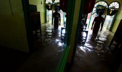 Warga berada di rumahnya yang terendam banjir di kawasan Kampung Rawajati, Jakarta, Senin (16/11).