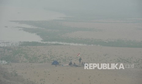 Warga berada di tepi Sungai Batanghari yang diselimuti kabut asap kebakaran hutan dan lahan (karhutla), Jambi, Selasa (15/10/2019). 