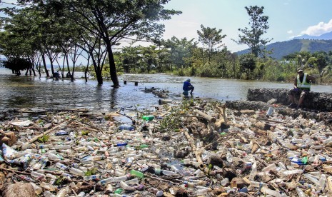 Warga berada diantara sampah yang terbawa akibat meluapnya danau Sentani di Waena Jayapura, Papua, Jumat, (29/3/2019).