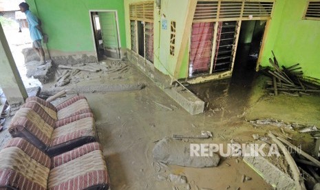 Warga berada disekitar rumahnya yang rusak dan terendam lumpur akibat diterjang banjir bandang di Desa Poi, Kabupaten Sigi, Sulawesi Tengah, Ahad (8/12/2019).