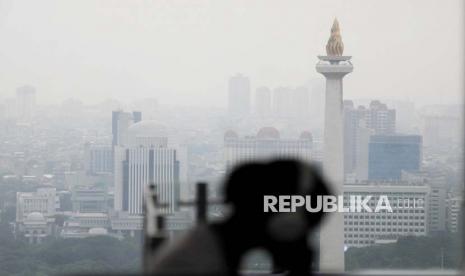 Warga beraktivitas dengan latar belakang gedung bertingkat yang terlihat samar karena polusi udara. Polusi udara memberikan dampak negatif bagi tubuh.