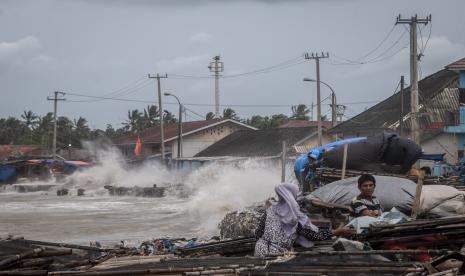 Warga beraktivitas di bibir pantai saat ombak menerjang kawasan tersebut di Teluk Labuan, Pandeglang, Banten. Badan Geologi mengimbau warga tidak mendekati Gunung Anak Krakatau radius 5 km.