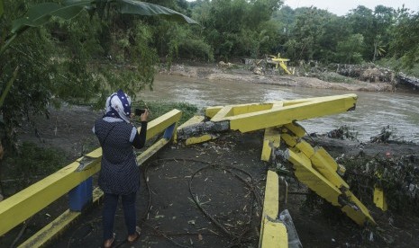 Warga beraktivitas di dekat jembatan yang rusak di Imogiri, Bantul, DI Yogyakarta, Kamis (30/11). Banyak jembatan penghubung antardesa di DIY dan wilayah Jawa Tengah putus diterjang banjir menyusul dampak dari siklon tropis Cempaka.. 