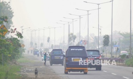 Warga beraktivitas di tengah kabut asap yang menyelimuti kota Padang, Sumatera Barat, Selasa (15/10/2019).