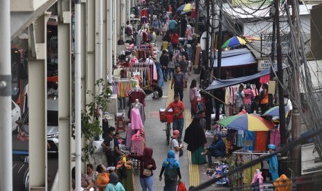 Warga berbagi jalan dengan pedagang kaki lima (PKL) yang berjualan di trotoar jembatan penyebrangan multiguna (skybridge) Tanah Abang, Jakarta, Rabu (15/5/2019). 