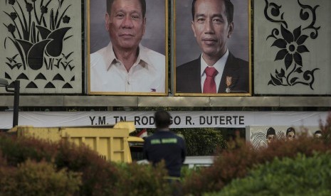 Warga berdiri di depan foto Presiden Joko Widodo dan Presiden Filipina Rodrigo Duterte yang dipajang di seberang Istana Merdeka, Jakarta, Kamis (8/9). 