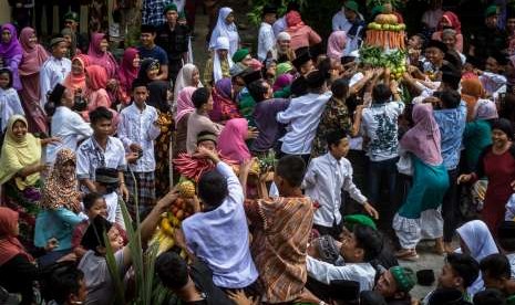 Warga berebut gunungan hasil bumi dalam prosesi Tradisi Grebeg Suro Girikusumo di Desa Banyumeneng, Mranggen, Demak, Jawa Tengah, Kamis (21/9). 