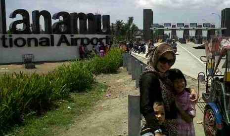 Warga berfoto di depan Bandara Internasional Kualanamu, Jumat (9/8). Liburan Hari Raya Idul Fitri, Bandara pengganti Polonia Medan ini menjadi objek wisata dadakan.