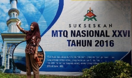 Warga berfoto di depan spanduk MTQ Nasional yang menghiasi jalanan di Kota Mataram, NTB, Kamis (14/7).