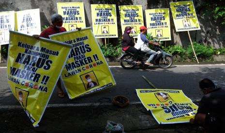 Warga bergotong royong memasang poster imbauan untuk memakai masker saat beraktivitas di Kampung Nayu, Banjarsari, Solo, Jawa Tengah, Rabu (8/4/2020). Pemasangan poster tersebut sebagai usaha warga setempat mencegah penyebaran virus COVID-19.