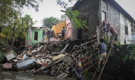 Warga bergotong royong membersihkan rumah yang longsor.