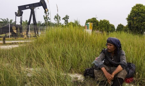 Warga beristirahat di dekat monumen pompa angguk minyak tertua di daerah Minas yang masuk dalam Blok Rokan di Riau, Rabu (1/8).