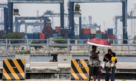 Warga berjalan dengan latar belakang suasana pelabuhan peti kemas di Pelabuhan Tanjung Priok, Jakarta, Selasa (18/10). 