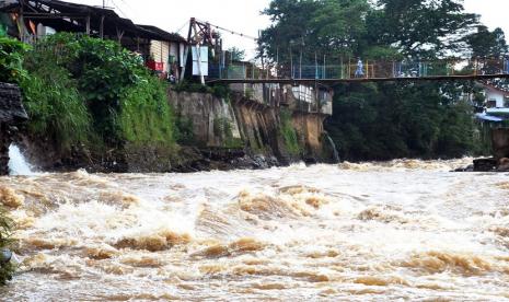 Warga berjalan di atas jembatan sungai Ciliwung yang arus airnya deras, di Kelurahan Sempur, Kota Bogor, Jawa Barat, Selasa (9/2). Direktur Peringatan Dini Badan Nasional Penanggulangan Bencana (BNPB) Afrizal Ari mengakui, Pulau Jawa termasuk Jabodetabek, memang akan mengalami potensi banjir dalam dua hari ke depan.