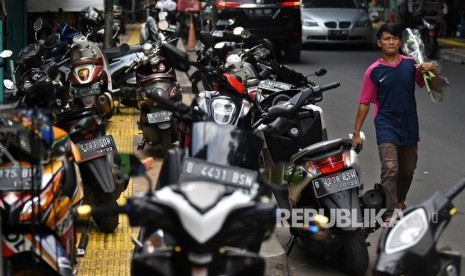 Warga berjalan di badan jalan raya karena trotoar ditempati parkir liar sepeda motor