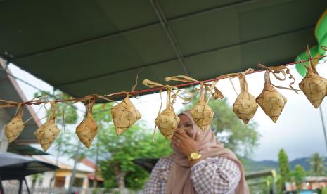 Warga berjalan di dekat ketupat yang dihidangkan saat tradisi Lebaran Ketupat di Kabila, Kabupaten Bone Bolango, Gorontalo, Senin (9/5/2022). Tradisi tersebut dilaksanakan satu pekan setelah Idul Fitri dengan makan ketupat dan hidangan lainnya secara bersama-sama, baik di rumah, lapangan hingga jalanan