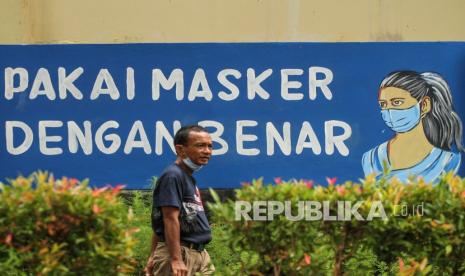 Warga berjalan di depan mural dengan tema COVID-19 di halaman Balai Kota Depok, Depok, Jawa Barat, Rabu (6/1/2021). Ilustrasi