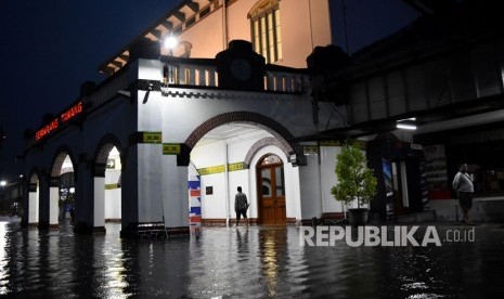 Warga berjalan di genangan air yang membanjiri ruang tunggu keberangkatan Stasiun Besar Kereta Api (KA) Tawang di Semarang, Jawa Tengah, Senin (3/12/2018) malam. 