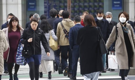 Warga berjalan di pusat Kota Tokyo, Senin (17/2). Pertumbuhan ekonomi Jepang tercatat melambat menjadi 6,3 persen akibat peningkatan pajak, dampak angin topan dan permintaan global yang lemah.