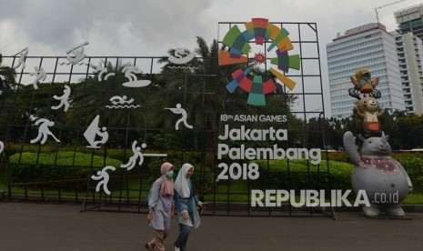 Warga berjalan di samping display promosi Asian Games 2018 di Kawasan Jalan Merdeka Selatan, Jakarta, Jumat (20/4).