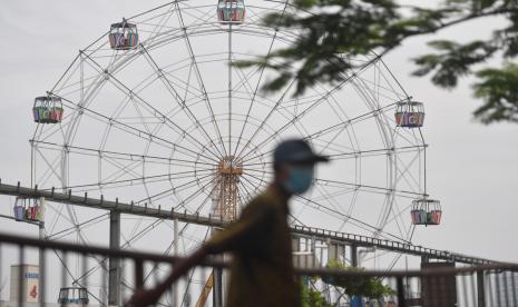 Warga berjalan di samping kawasan Suroboyo Carnival Park yang telah dibongkar di Surabaya, Jawa Timur, Senin (25/1). Plt Wali Kota Surabaya, Whisnu Sakti Buana sependapat dengan Presiden Joko Widodo yang menyatakan, penerapan Pemberlakukan Pembatasan Kegiatan Masyarakat (PPKM) tidak efektif. Bahkan berdasarkan data yang diperolehnya saat mengikuti rapat koordinasi dengan Menko Maritim dan Investasi pada Ahad (31/1) malam, penambahan kasus Covid-19 harian masih tinggi, meski PPKM diterapkan hampir tiga pekan.